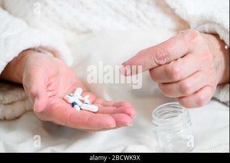 Donna anziana che prende le medicine che prendono le pillole dalla mano, vista del closeup. Foto Stock