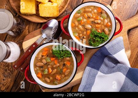 Vista dall'alto di due ciotole di gustosa zuppa di fagioli con carote e sedano su un tavolo di legno Foto Stock