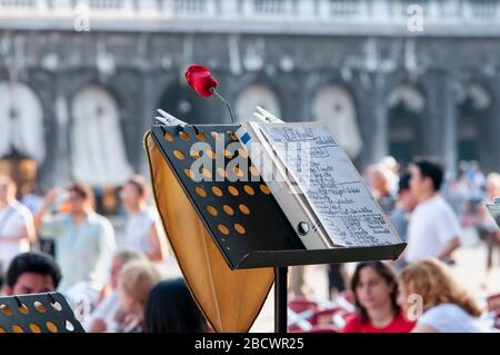 Dove si nascondeva il musicista? Leggio musicale in un bar in Piazza San Marco a Venezia. Caffè a Venezia con tanti turisti sullo sfondo soffice. Foto Stock