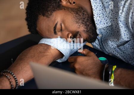 Uomo afro-americano esausto addormentarsi sul posto di lavoro Foto Stock
