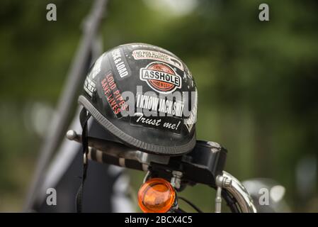 Casco per moto coperto da emblemi, appeso su una moto a un rally Thunder. Foto Stock