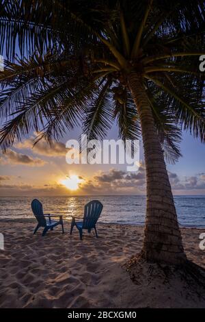 Un tramonto perfetto con sedie da spiaggia, Grand Cayman Island Foto Stock