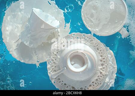Concetto di piatti, piastre e tazze in porcellana imbevute di ondulazione d'acqua Foto Stock