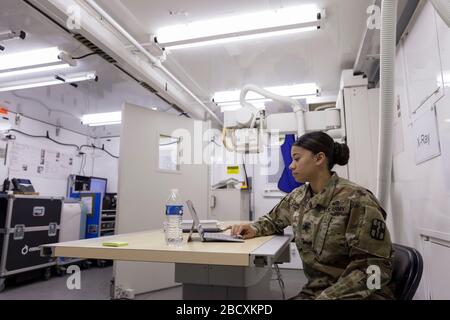 Il sergente Jordan Lambert, un tecnico radiogeno, prepara l'unità radiologica per i pazienti presso l'ospedale di campo del CenturyLink Field Event Center di Seattle il 5 aprile 2020. L'ospedale chirurgico dell'esercito mobile, attualmente per casi non COVID-19, coinvolge personale medico militare di più unità, compresi i soldati del 627° Hospital Center's 10th Field Hospital a Fort Carson, Colorado, la 62a Medical Brigade dalla Joint base Lewis-McChord, Washington e altri. I funzionari hanno detto che l'ospedale è ora pronto ad accettare i pazienti. Foto Stock