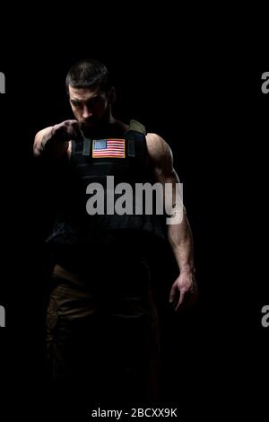 Bodybuilder Ritratto di Soldato con Bulletproof Vest e noi bandiera su uno sfondo nero Foto Stock