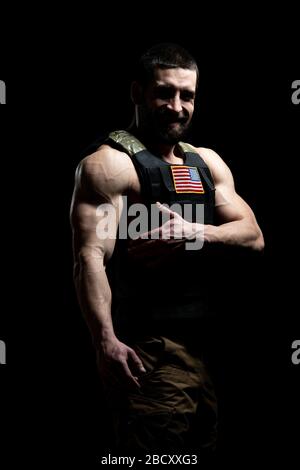 Bodybuilder Ritratto di Soldato con Bulletproof Vest e noi bandiera su uno sfondo nero Foto Stock