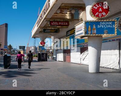 4 aprile 2020, Las Vegas, Nevada, USA, due donne che camminano sul deserte Las Vegas Boulevard di fronte ai negozi a bordo a causa della chiusura di Covid-19 Foto Stock