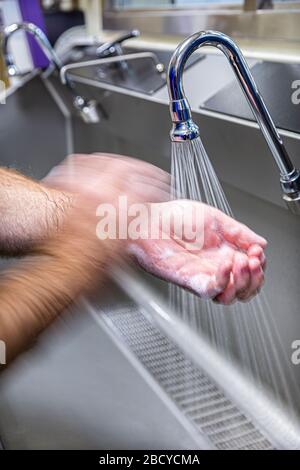 Il medico pulisce e sfrega le mani con sapone e acqua sopra un lavandino. Foto Stock