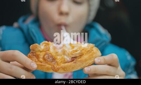 Bambino mangiare pizza formaggio quattro. Primo piano di ragazza giovane donna mangiare pizza e masticare in ristorante all'aperto. Bambini mani prendere pezzo pizza. Foto Stock