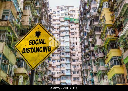 Segnale di avvertimento di distanza sociale di fronte a un affollato pubblico immobiliare a Quarry Bay, Hong Kong. Concetto di importanza della distanza fisica a p Foto Stock