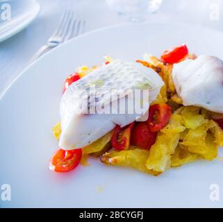 spigola al forno con verdure fritte e pomodori ciliegini saltati con erbe aromatiche Foto Stock