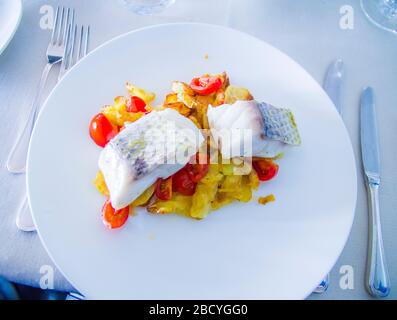 spigola al forno con verdure fritte e pomodori ciliegini saltati con erbe aromatiche Foto Stock