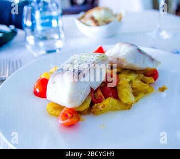 spigola al forno con verdure fritte e pomodori ciliegini saltati con erbe aromatiche Foto Stock
