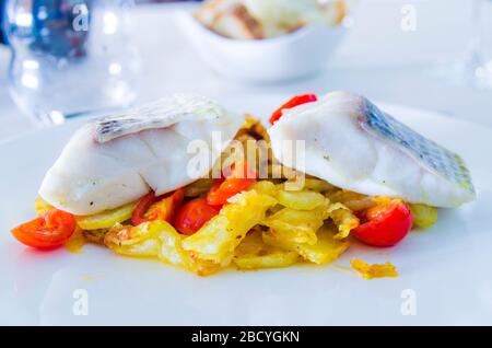 spigola al forno con verdure fritte e pomodori ciliegini saltati con erbe aromatiche Foto Stock