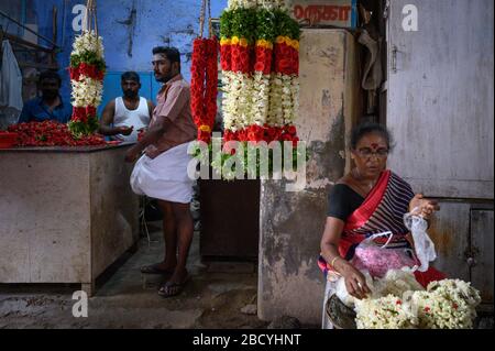 Donna che ordina i fiori sui terreni del tempio di Tiruchendur Murugan, Tiruchendur, India Foto Stock