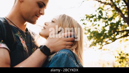 Foto ravvicinata del forte uomo caucasico che abbraccia la sua ragazza e guarda negli occhi Foto Stock