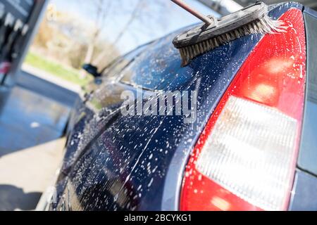 Lavare a mano l'auto con una spazzola in schiuma. Autolavaggio