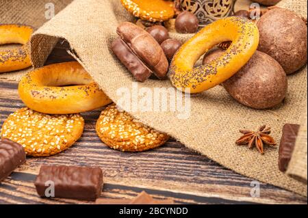 Bagel, anice stellato, biscotti, torte al cioccolato e cioccolato su uno sfondo di tessuto omespun grossolano. Primo piano Foto Stock