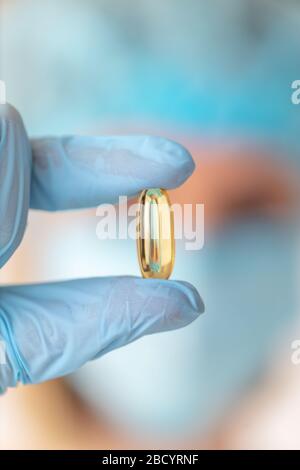 Giovane attraente male femminile o medico con guanti e maschera tenendo una capsula in mano. Concetto di medicina Foto Stock