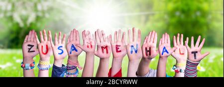 Kids Hands Holding Word Zusammenhalt significa insieme, prato erba Foto Stock