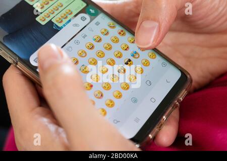 donna invia emoticon divertenti su un'applicazione di messaggistica istantanea Foto Stock
