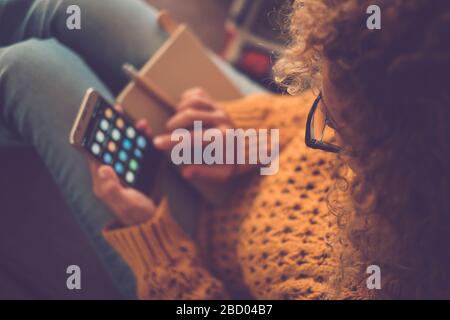 Primo piano di una donna vista dall'alto utilizzando uno smartphone a casa per lavoro o social media che condividono attività di vita - concentrarsi sugli occhiali e la schiena disfocalizzata Foto Stock