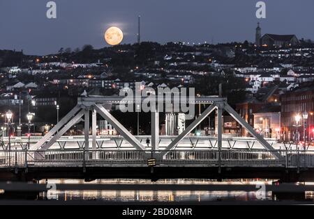 Cork City, Cork, Irlanda. 06 aprile 2020. Una vista del Ponte Brian Boru e del lato nord della città mentre una luna ardente gibbous desends nella città di Cork, Irlanda. - credito; David Creedon / Alamy Live News Foto Stock
