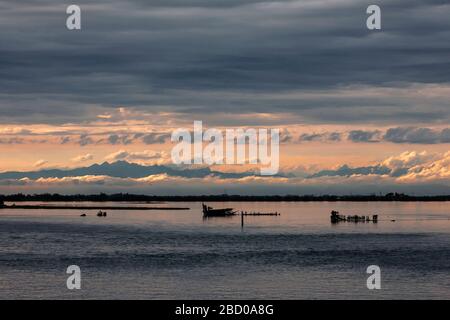 Tramonto sulla Laguna di grado, con le Dolomiti oltre, Friuli-Venezia Giulia, Italia Foto Stock