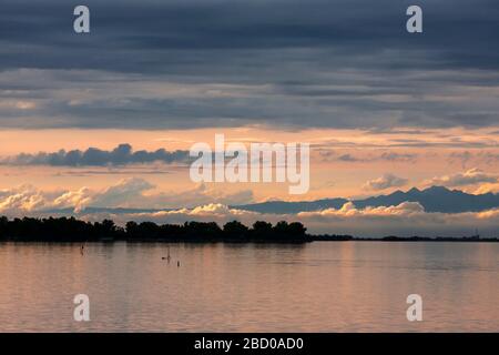 Tramonto sulla Laguna di grado, con le Dolomiti oltre, Friuli-Venezia Giulia, Italia Foto Stock