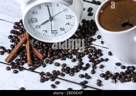 sveglia retrò, tazza di caffè, caffè in grani e cannella su un tavolo di legno Foto Stock