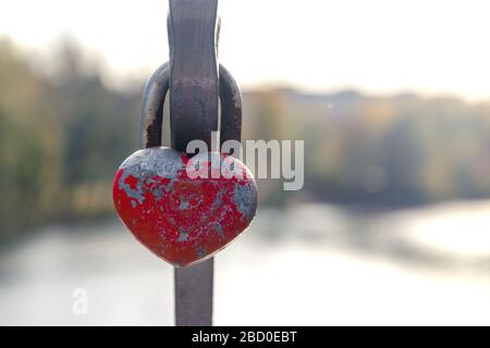 lucchetto rosso shabby a forma di cuore. i graffi simboleggiano l'amore forte. cuore appeso all'aria aperta. concetto di amore. Tema San Valentino Foto Stock