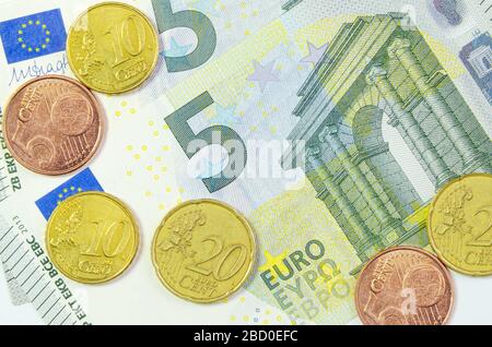 Monete in centesimi di euro su 2 banconote da 5 euro che simboleggiano l'inflazione e i debiti. Primo piano Foto Stock