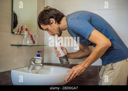 Un uomo usa un irrigatore orale nel suo bagno Foto Stock