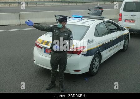 Un membro della polizia di frontiera israeliana indossa la maschera facciale mentre guida il traffico sulla strada durante lo scoppio della malattia di coronavirus (COVID-19) in Israele Foto Stock