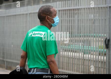 Un lavoratore migrante che indossa maschera facciale a causa delle passeggiate della pandemia di coronavirus COVID-19 nel quartiere di neve Shaanan, che divenne sede di una delle più grandi popolazioni di africani e altri migranti nel sud di Tel Aviv Israele Foto Stock