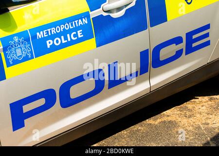 Vista angolata del cartello della polizia metropolitana sulla porta laterale della vettura di pattuglia a risposta rapida coperta di blu e giallo ad alta visibilità. Foto Stock