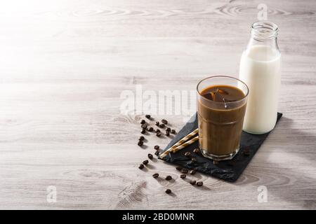Caffè ghiacciato o latte di caffe in un alto vetro su tavolo di legno. Spazio di copia Foto Stock