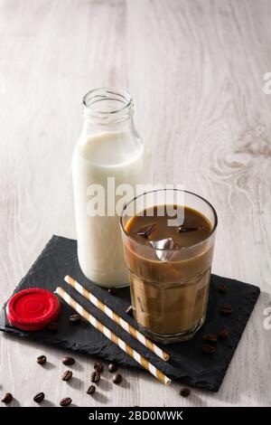 Caffè ghiacciato o latte di caffe in un alto vetro su tavolo di legno Foto Stock