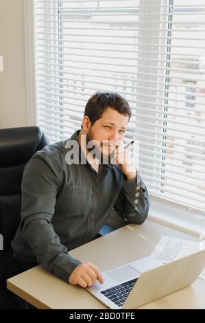 Uomo d'affari che lavora in ufficio con un laptop e una penna. Foto Stock