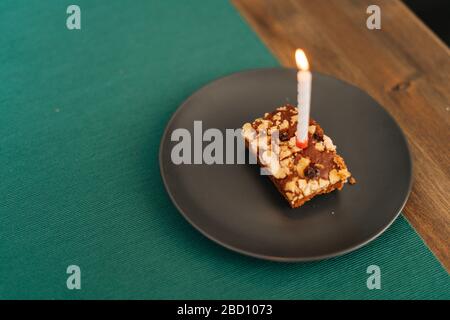 Primo piano torta con candela bruciante in camera luminosa. Foto Stock