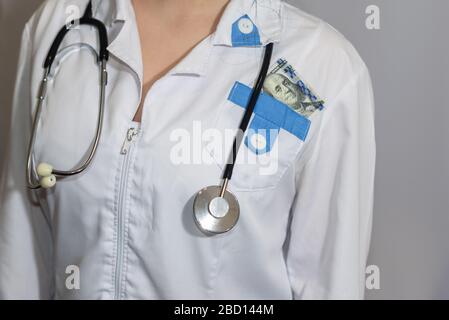 Tangente. Cento dollari di fattura in tasca di un medico o paramedico. Corruzione in medicina, farmaceutica. Il concetto di medicina pagata. Foto Stock