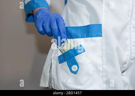 Un medico o paramedico nasconde un centenario della sua tangente. Corruzione in medicina, farmaceutica. Il concetto di medicina pagata. Foto Stock