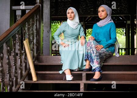 Ritratto di donne malesi musulmane che indossano hijab e costume tradizionale durante le celebrazioni Aidilfitri sulla terrazza della casa tradizionale in legno. Hari R Foto Stock