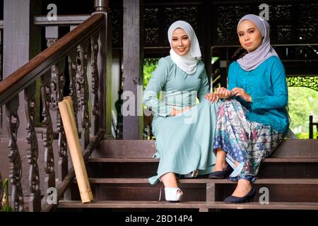 Ritratto di donne malesi musulmane che indossano hijab e costume tradizionale durante le celebrazioni Aidilfitri sulla terrazza della casa tradizionale in legno. Hari R Foto Stock