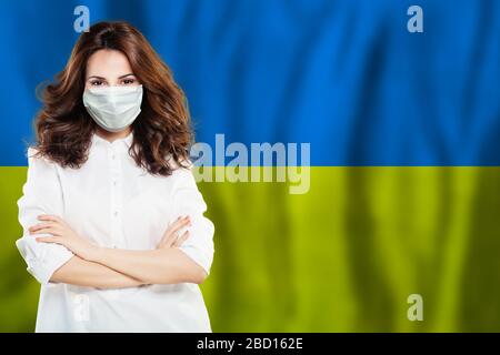 Medico o infermiere in maschera facciale di sicurezza medica sullo sfondo della bandiera Ucraina. Influenza epidemica e protezione del virus in Ucraina concetto Foto Stock