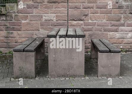 Panchine di legno sul lungomare. Tavolo sotto la parete. Rilassati e riposati sul campo. Muro di mattoni. Foto Stock