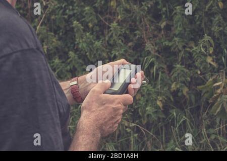 Uomo in possesso di un ricevitore GPS in mano. Dispositivi palmari GPS sono utilizzati prevalentemente per l'outdoor industria del tempo libero per escursioni e passeggiate. Foto Stock