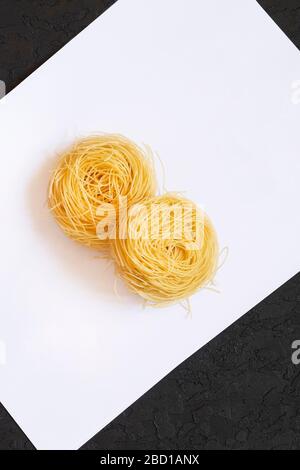 Tagliatelle di pasta italiana su fondo bianco e nero. Capelli lunghi, capelli mossi, capelli lisci. Cucina italiana. Tagliatelle di uovo. Pasta italiana Foto Stock