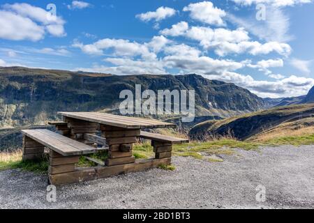 Panca in legno, punto di osservazione per le montagne norvegesi. Viaggio nel parco naturale scandinavo. Vista sulla valle dalla zona di riposo vicino alla strada Foto Stock