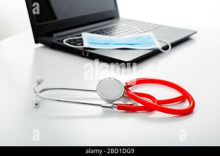 Stetoscopio e maschera protettiva chirurgica sul laptop. Medicina salute concetto. Medici posto di lavoro per video chiamata chat, consultazione online, medico Foto Stock